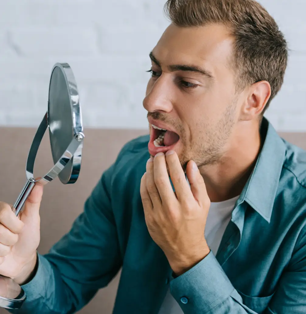 Man staring at his mouth in the mirror